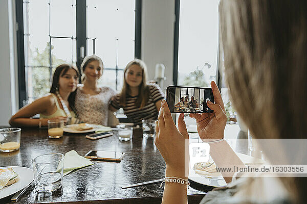 Group of teenage girls meeting for brunch  taking smartphone pictures