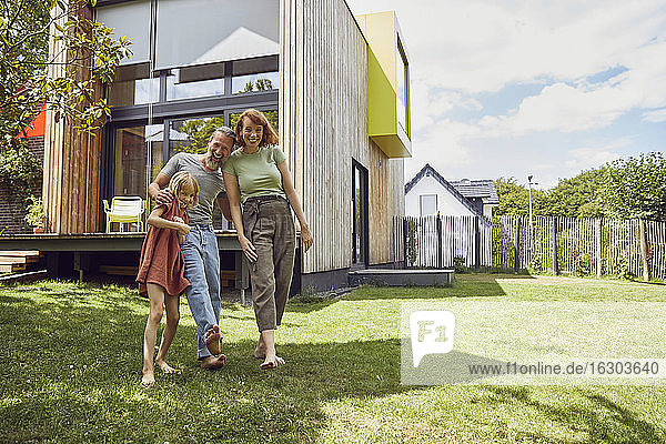 Cheerful parents with daughter standing against tiny house in yard