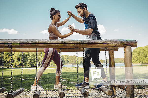 Mann und Frau kämpfen auf einem Fitnessparcours auf Balancierstämmen