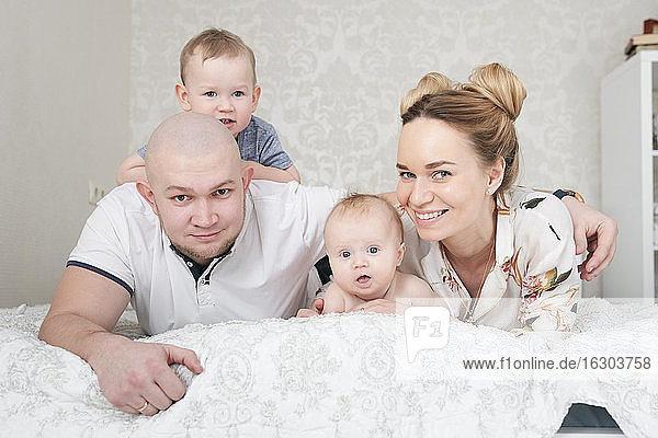 Happy parents with two children lying on bed