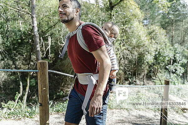 Vater wandert mit seinen Kindern und trägt seinen Sohn auf dem Rücken