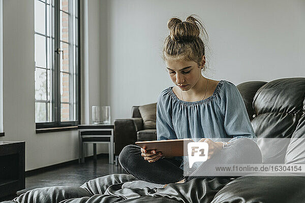 Mädchen  das ein digitales Tablet benutzt  während es sich auf dem Sofa zu Hause entspannt