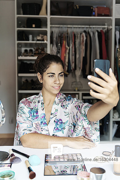 Junge Frau  die ein Selfie mit ihrem Smartphone macht  während sie zu Hause sitzt