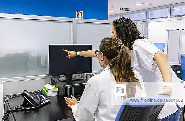 Female pharmacists discussing over computer in hospital