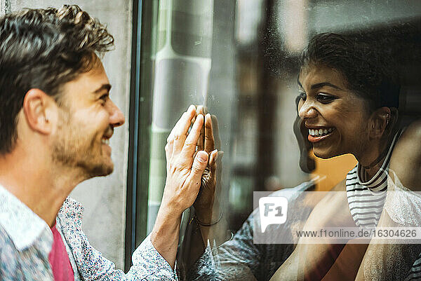 Nahaufnahme eines lächelnden Paares  das sich durch ein Fenster ansieht