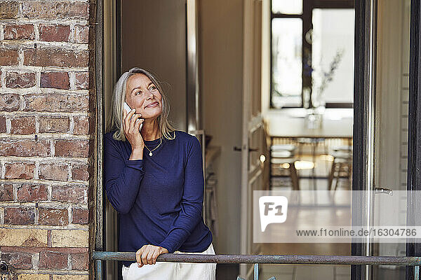 Lächelnde Frau  die auf einem Balkon telefoniert