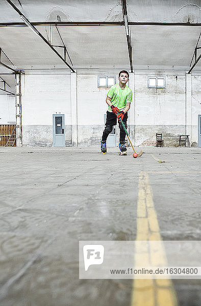 Surface level view of boy practicing roller hockey at court