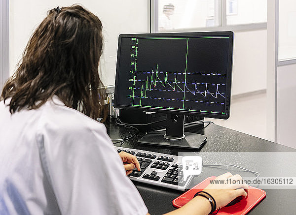 Weiblicher Arzt analysiert Liniendiagramm über Computer im Krankenhaus
