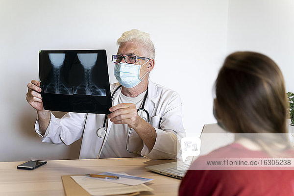 Arzt gibt jungen Patienten Ratschläge bei der Analyse von Röntgenaufnahmen