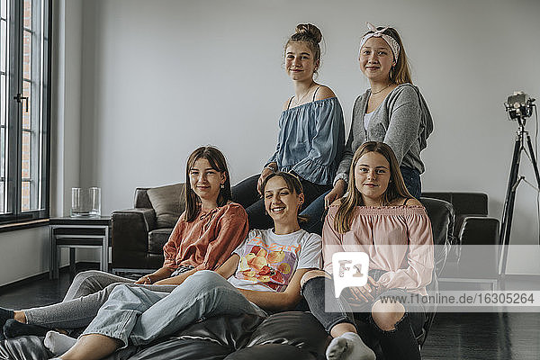 Smiling friends sitting on sofa in loft apartment