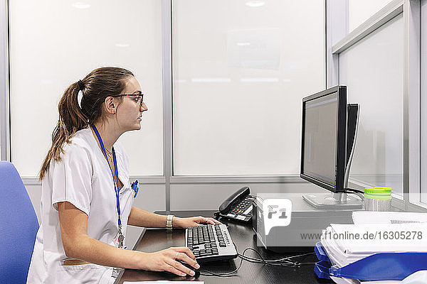 Female pharmacist using computer on desk in pharmacy