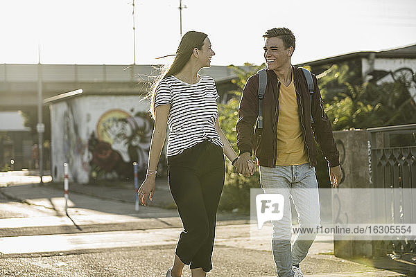 Glückliches junges Paar  das sich beim Gehen auf der Straße an den Händen hält