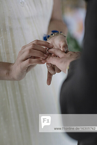 Bride putting wedding ring in groom's finger