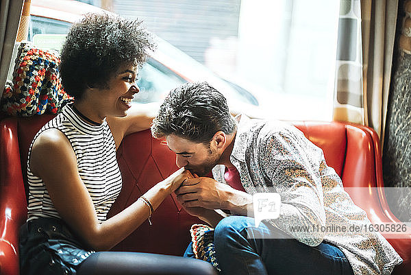 Romantischer Mann küsst die Hand seiner Freundin  während er in einem Café sitzt