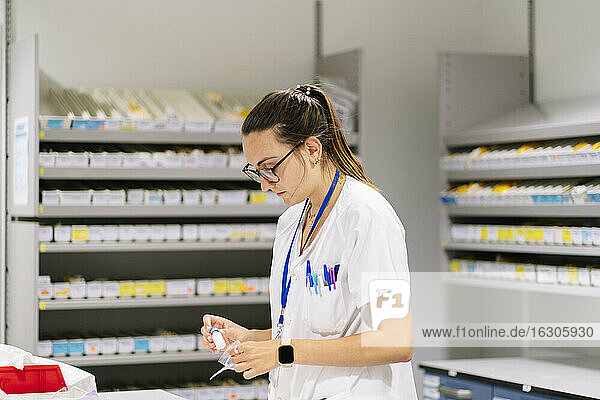 Weibliche Mitarbeiterin beim Verpacken von Medikamenten in der Apotheke stehend