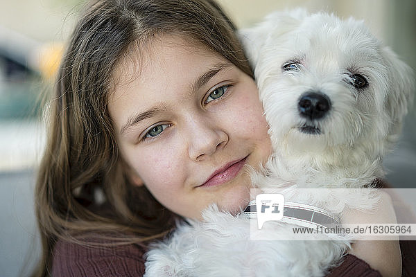Nettes lächelndes Mädchen umarmt Hund im Wohnzimmer