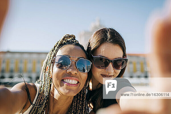Smiling woman taking selfie with friend at Praca Do Comercio  Lisbon  Portugal