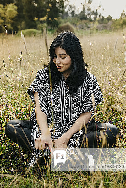 Beautiful woman looking down at grass while sitting in public park