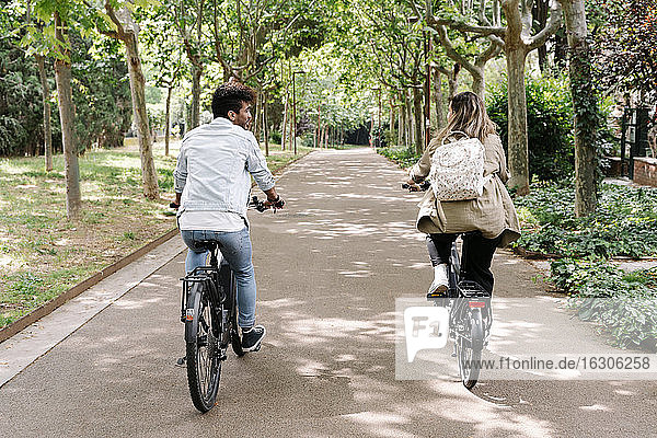 Young couple riding electric bicycles on road
