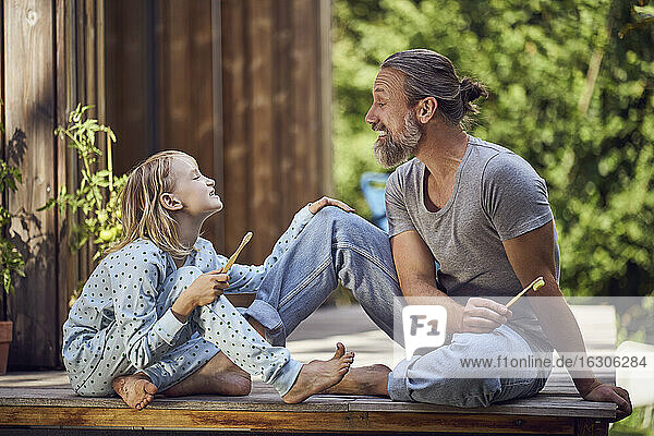 Vater und Tochter zeigen sich gegenseitig die Zähne  während sie im Hof sitzen