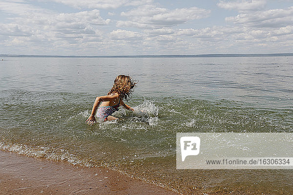 Kleines Mädchen genießt beim Spielen im Wasser am Strand