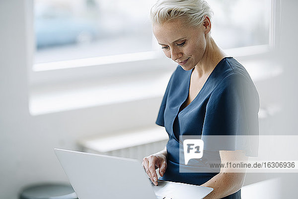 Geschäftsfrau mit Laptop im Loft-Büro sitzend
