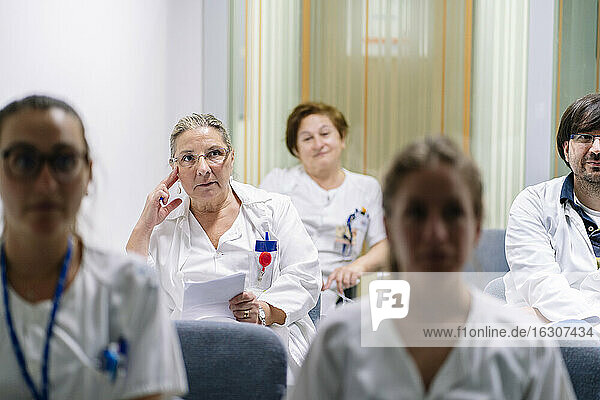 Doctors listening while sitting in meeting at board room