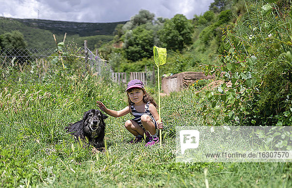 Nettes Mädchen hockt bei Hund in grünem Feld während sonnigen Tag