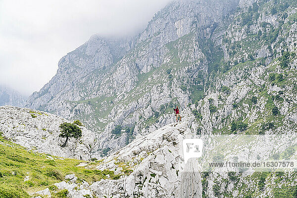 Junger Mann bewundert die Aussicht  während er auf einem Berg an der Ruta Del Cares steht  Asturien  Spanien