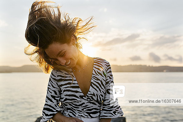 Beautiful woman tossing hair against clear sky