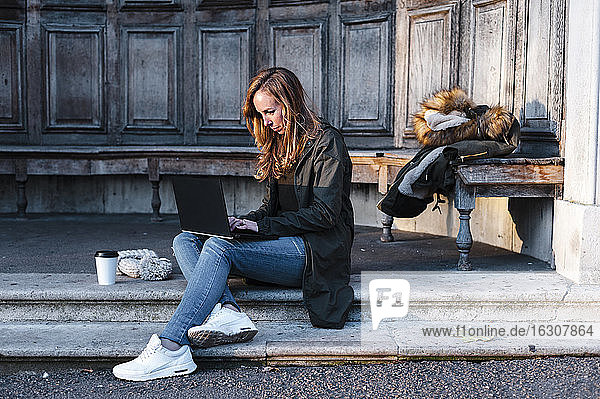 Businesswoman sitting at park while working on laptop