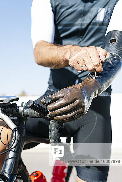 Close-up of male cyclist wearing artificial hand on bicycle