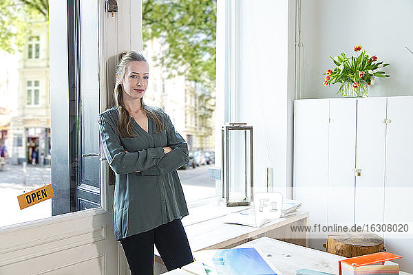Portrait of woman leaning against glass door in office