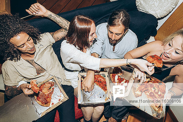 Friends enjoying pizza during social gathering at home