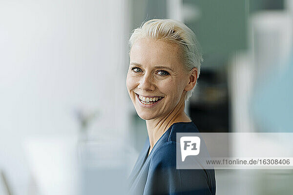 Close-up of cheerful businesswoman with short hair in office
