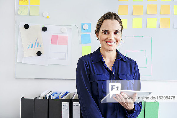 Selbstbewusste  kreative Geschäftsfrau mit digitalem Tablet im Büro