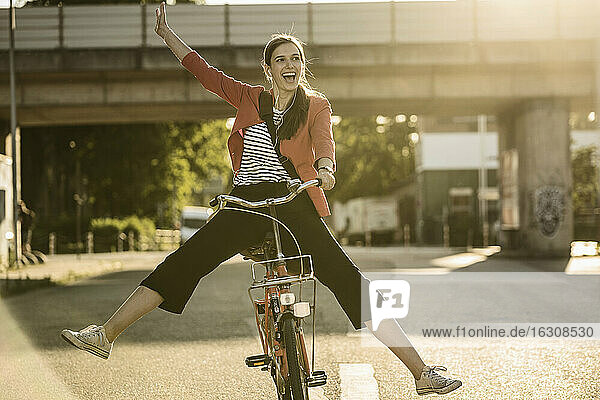 Fröhliche Frau genießt das Radfahren auf der Straße in der Stadt an einem sonnigen Tag