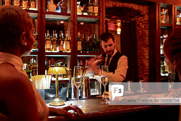 Barkeeper  der einen Cocktail mixt  während er an der Theke eines Pubs steht