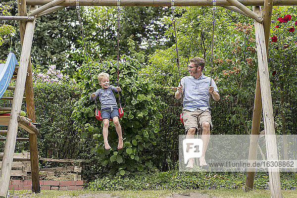 Vater und Sohn genießen das Schwingen gegen Pflanzen im Hinterhof
