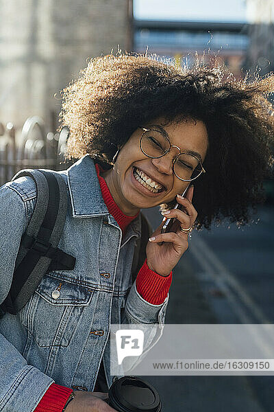 Nahaufnahme einer fröhlichen afroamerikanischen Frau  die über ein Smartphone in der Stadt spricht