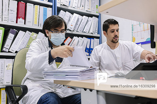 Männliche Ärzte erledigen Papierkram auf dem Schreibtisch in der Apotheke eines Krankenhauses