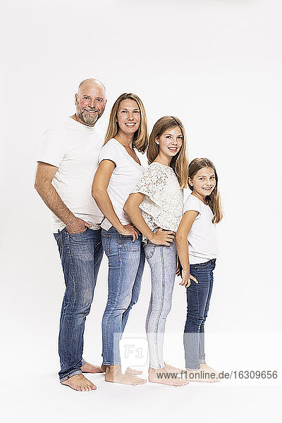 Lächelnde Familie mit Händen in den Hüften vor weißem Hintergrund