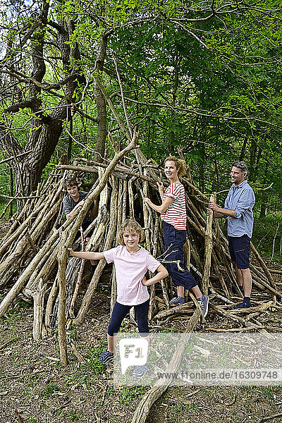 Glückliche Familie baut Lager mit Baumstamm im Wald