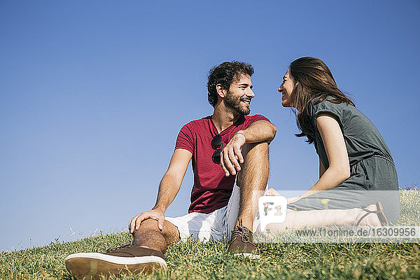 Mann schaut Frau an  während er im Gras sitzt
