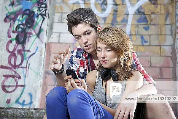 Germany  Berlin  Teenage couple on mobile phone