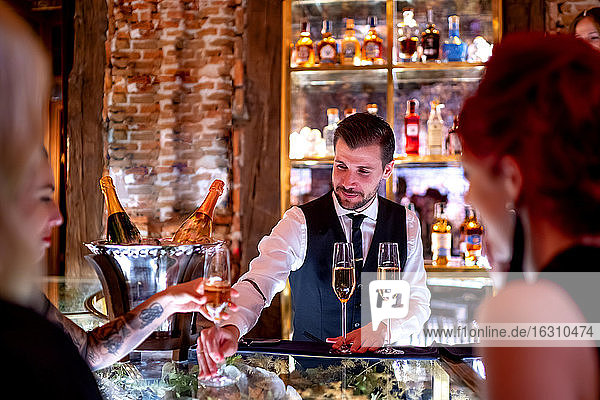 Barkeeper serviert Frauen an der Theke eines Pubs Getränke