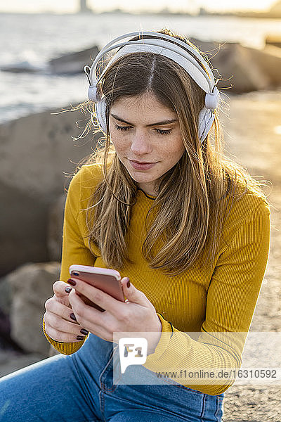 Nachdenkliche Frau mit Handy beim Musikhören in der Stadt