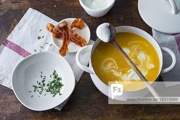 Preparation on carrot soup with bacon and creme fraiche