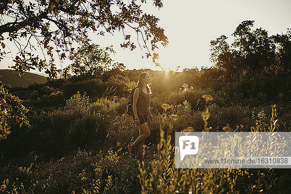 Frau schaut weg  während sie bei Sonnenuntergang im Wald steht