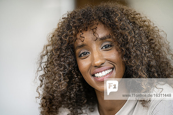 Nahaufnahme einer lächelnden Unternehmerin mit lockigem Haar im Büro